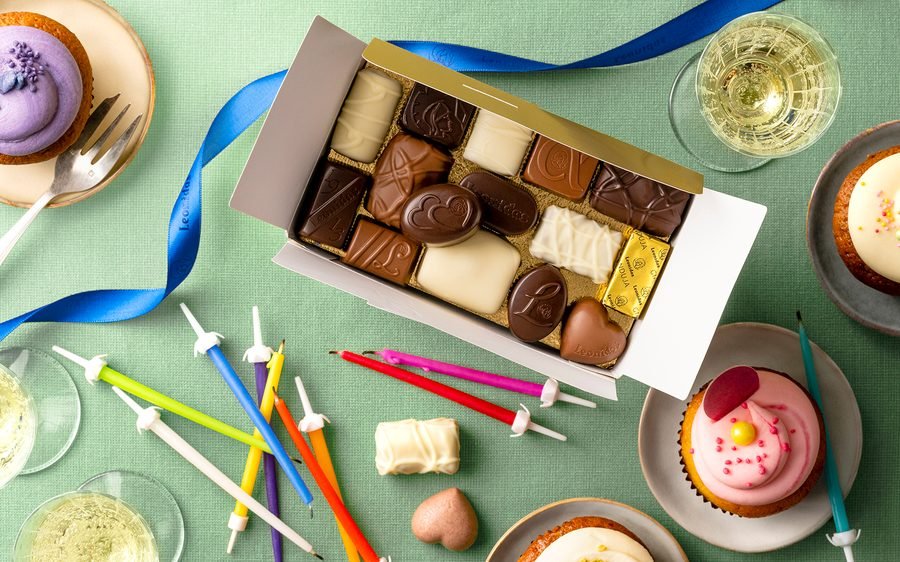 Leonidas pralines on a birthday table with candles and cupcakes